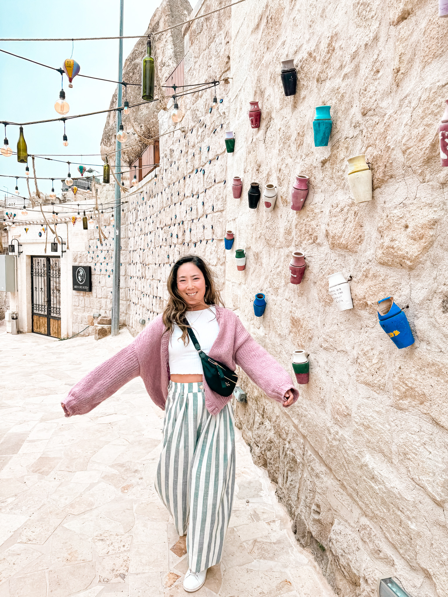 Erika walking through side street in Gerome in Cappadocia with pots and evil eyes decorating the walls.