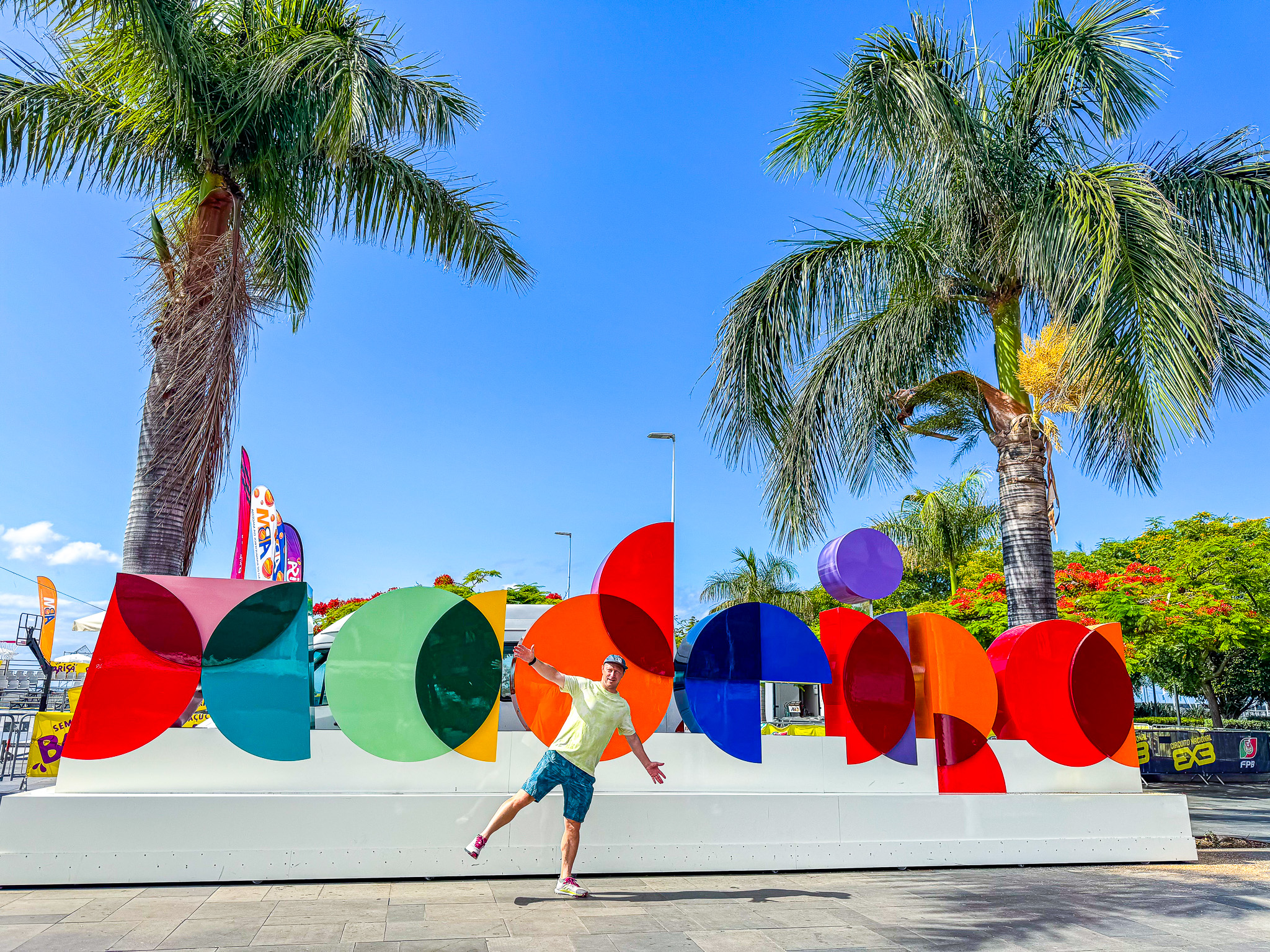 Mark in front of the colorful Madeira sign at the marina with palm trees and blue skies